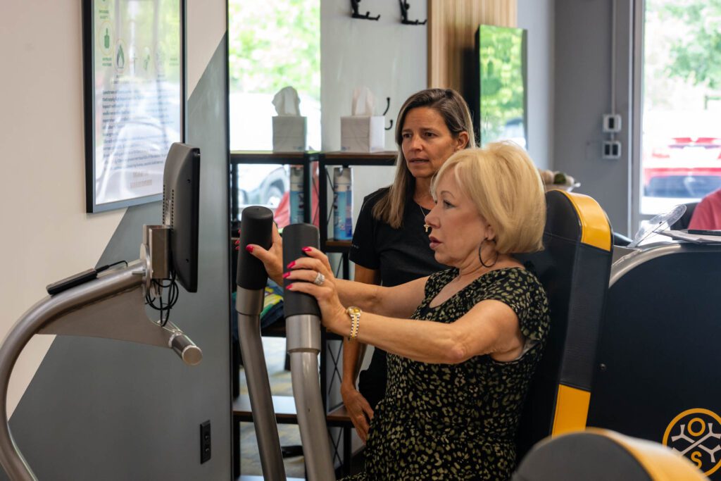 Woman using exercise machine with assistance.