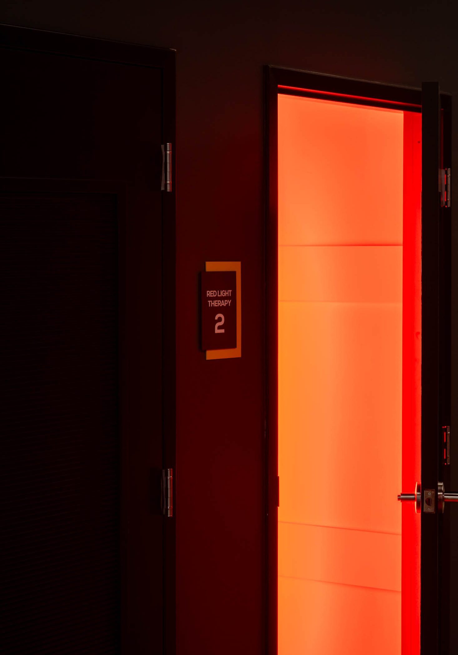 Red-lit open door in dim hallway.